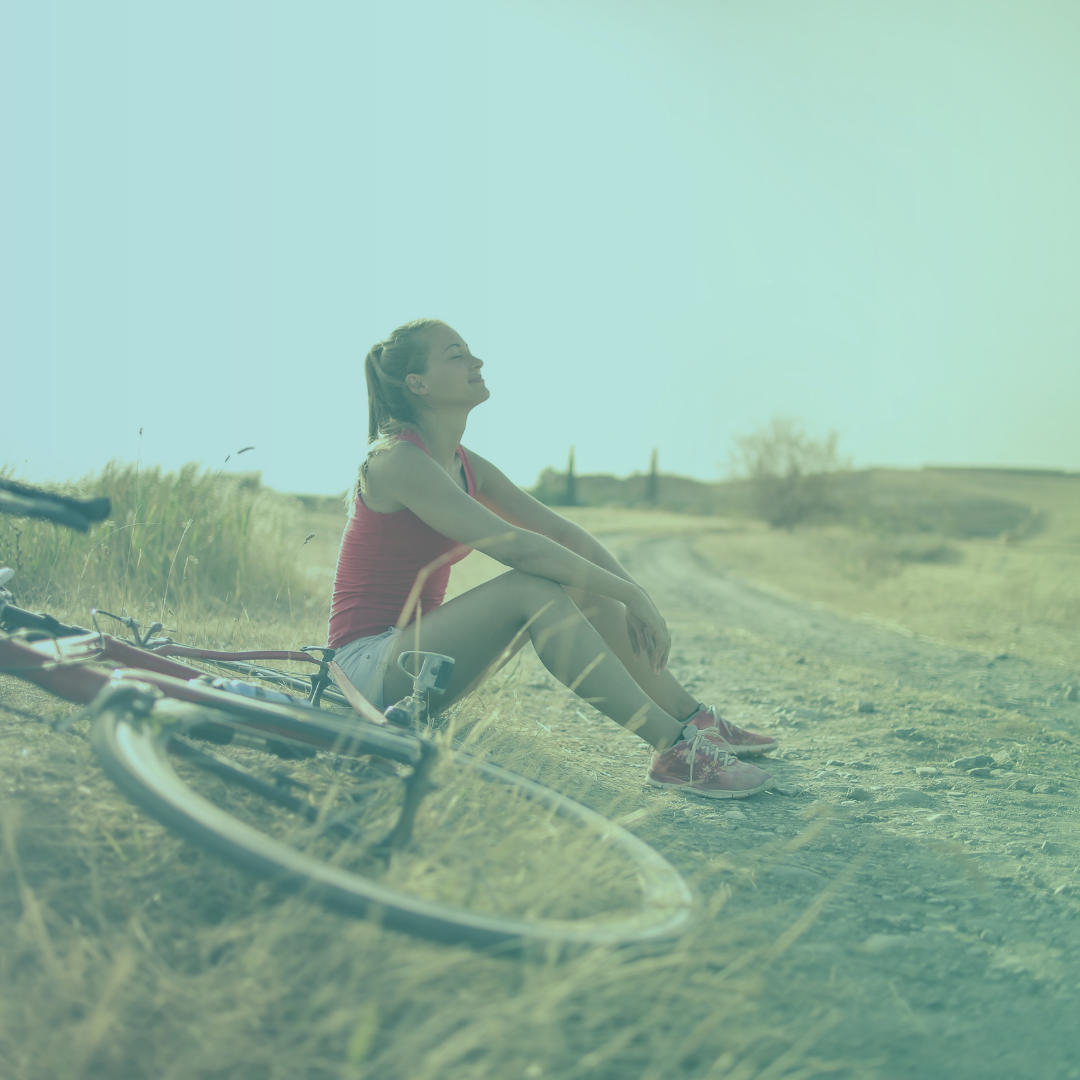 Female taking a breather by her bicycle on trail