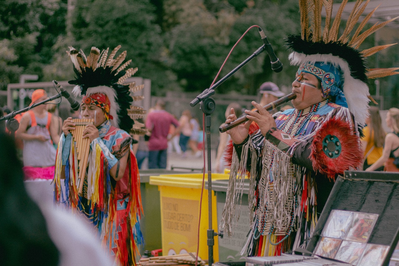 Two Indigenous people playing instruments